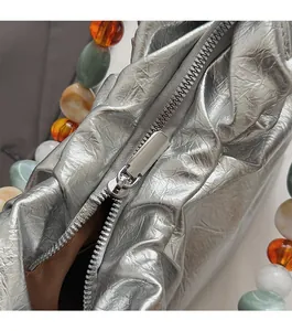 Detail of silver pleated bucket bag featuring metallic texture and colorful beads