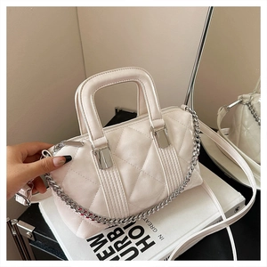 Detailed macro of white quilted faux leather texture with silver chain on Boston bag