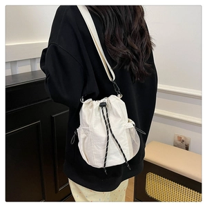 Detailansicht einer weißen Kordelzug-Beuteltasche mit schwarz-weißen Seilriemen und Netztasche