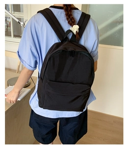 Detailed view of black nylon backpack with durable straps and front zipper pocket