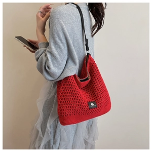Détail du sac cabas en crochet rouge avec bandoulière en cuir et étiquette de marque