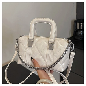 Detailed close-up of a white quilted pillow bag with silver chain handle and embroidery