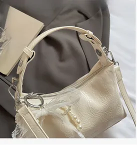 Détail du sac en cuir verni blanc cassé avec perles et garniture en maille dentelle