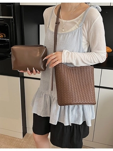 Ensemble sac seau tressé marron et pochette en cuir lisse dans un décor d'intérieur