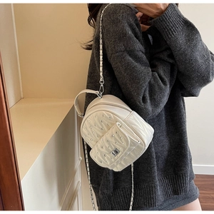 Close-up of white quilted leather backpack with silver studs and metal twist lock detail
