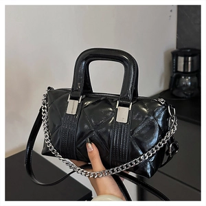 Detail of black quilted patent leather bag with silver chain and adjustable shoulder strap