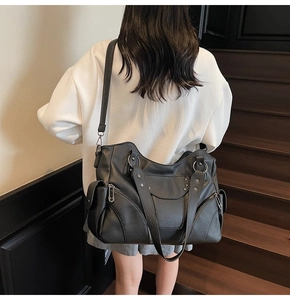 Mannequin portant un grand sac cabas noir à rivets et étoiles sur un escalier en bois