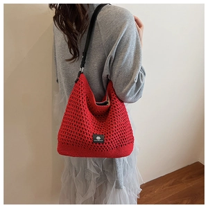 Vue détaillée du sac à bandoulière rouge en maille avec sangle en cuir noir et étiquette