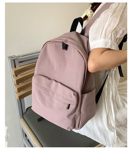 Detail view of a minimalist dusty rose backpack on a chair in a clean lifestyle setting