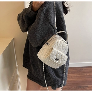 Detail of white quilted mini backpack with rhinestones and chain strap on a model