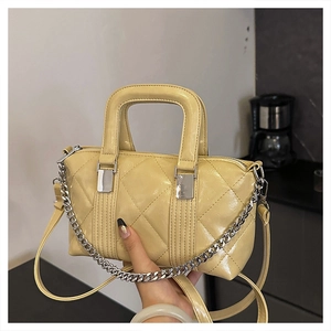 Detail of yellow quilted Boston bag with silver chain strap and top handles