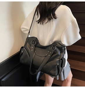 Détail du sac cabas en cuir noir avec clous en forme d'étoile argentée et boucles métal