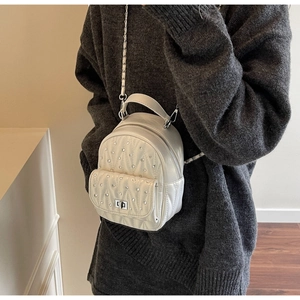 Close-up of white quilted leather mini backpack featuring silver rhinestone studs and chain