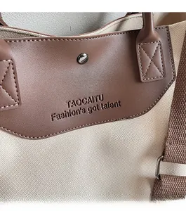 Detail of canvas tote bag showing dark brown leather embossing and magnetic closure