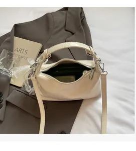Détail du sac à main en cuir verni blanc cassé avec breloque perle et noeud en dentelle