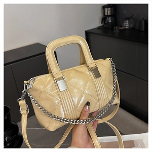 Close-up of cream quilted patent leather handbag with silver chain and stitch details