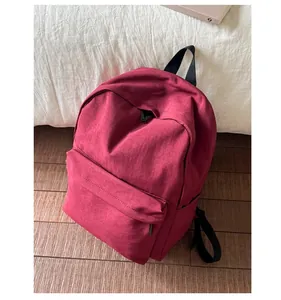 Detail of dark red nylon backpack with black zipper and front storage pocket