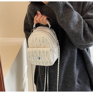 Detailed view of white quilted mini backpack with silver rhinestones and chain strap