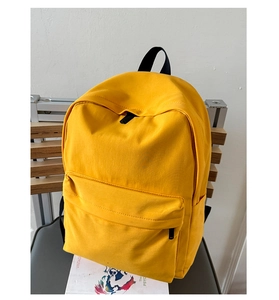 Detail of a bright yellow canvas backpack with large main compartment and front pocket