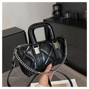 Detail of black quilted leather handbag with silver chain straps and glossy finish