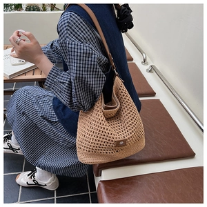 Detail of hand-woven hollow knit bag featuring leather straps and side logo patch