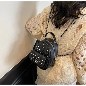 Detail of black quilted leather mini backpack with silver rivets and metal chain strap