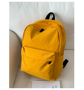 Detailed close-up of a minimalist bright yellow canvas backpack on a soft fabric sofa