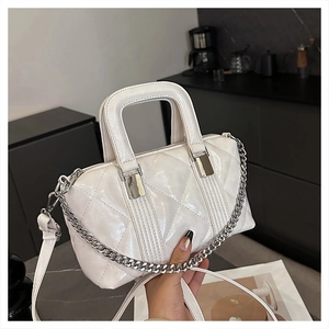 Detail of white quilted handbag with glossy finish, silver chain, and top handle strap