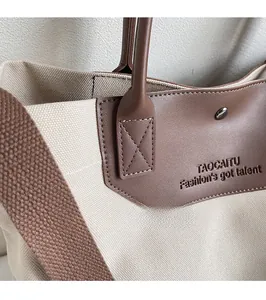 Close-up of canvas and leather tote bag featuring reinforced stitching and metal rivets
