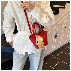 Détail du sac seau rouge à texture tressée avec un charmant pendentif petit ours