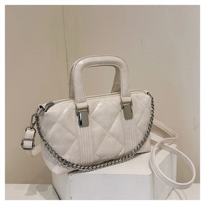 Detailed macro view of cream patent leather quilted bag with silver chain and glossy finish