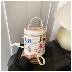 Detail shot of white bucket bag featuring colorful graffiti illustrations and golden metal buckles