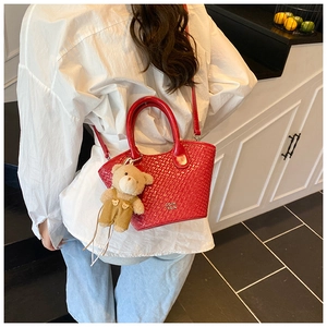 Détail du sac bandoulière rouge tressé avec logo doré et pendentif ourson en peluche mignon