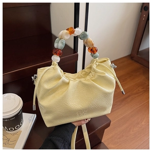 Detail of drawstring bucket bag with colorful bead handle on wooden stairs