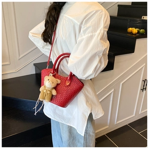 Détail du sac à bandoulière tissé rouge avec adorable breloque en peluche d'ourson