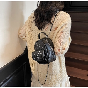 Detail shot of mini black quilted backpack with silver studs and metal chain straps