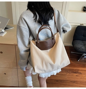 Model view showing the large canvas tote bag with brown leather handles and shoulder strap