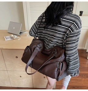 Détail du sac moto marron foncé avec rivets, cuir texturé litchi et fermetures éclair en métal