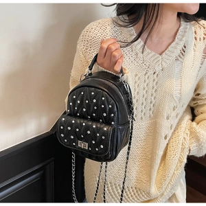 Detail of mini black quilted leather backpack with silver rhinestones and chain straps