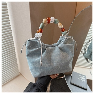 Close-up of denim bucket bag with sparkling studs and colorful beaded handle