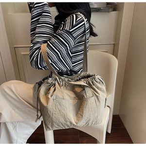 Detail of khaki nylon tote bag showing side pocket and lightweight pleated texture