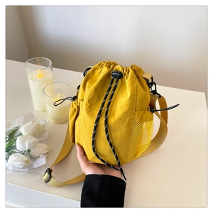 Makroaufnahme einer leuchtend gelben Kordelzug-Beuteltasche mit seitlicher Netztasche und Kordel
