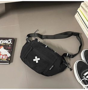 Detail view of a black nylon utility fanny pack with mesh pocket and white cross logo