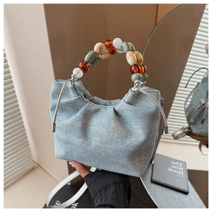 Detail of light blue pleated bucket bag with sparkling rhinestones and colorful resin beads
