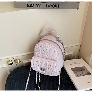 Detailed macro view of pink quilted leather backpack with silver studs and chain strap