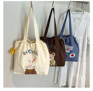 Detail of embroidered canvas tote bags with drawstring closure and cute animal patterns