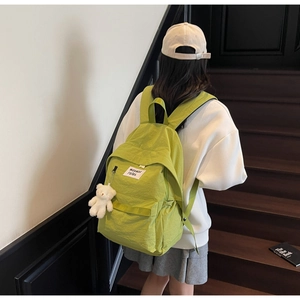Dettaglio dello zaino in nylon verde avocado con peluche di orso bianco indossato dal modello