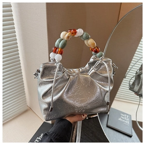 Detail of metallic silver pleated bucket bag with colorful beaded handle and drawstring
