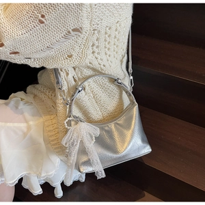 Détail du sac à main plissé argenté avec nœud en dentelle et breloque perle élégante
