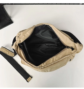 Detail view of khaki nylon crossbody bag showing spacious black lining and zip closure
